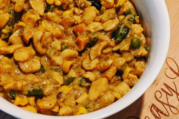 Cashew curry with carrots and green peas in a white bowl