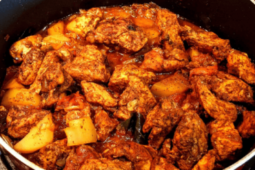 Brown chicken curry with potato pieces, covered with spices