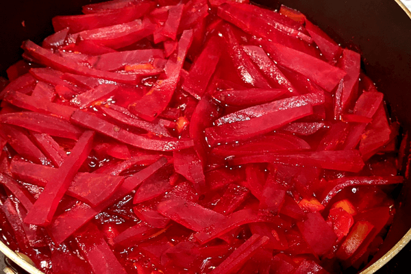 Chopped beets with seasonings and water cooking on a pan