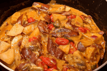 Red curry with eggplant, tomato and potatoes in a pan