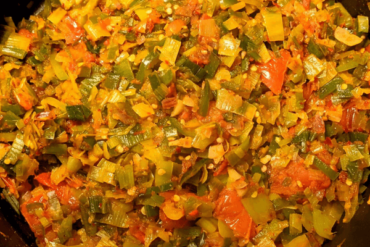Leeks fried with tomatoes, onions and chilies on a pan