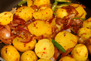 potatoes fried on a pan, with onions and green chilies