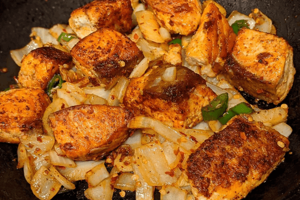 Fried salmon bites dish with onions, garlic, chilies and curry leaves.