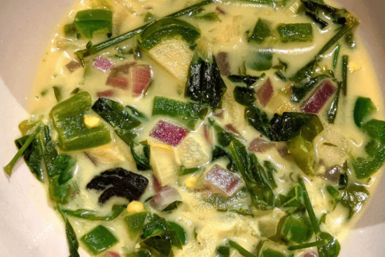 Mukunuwenna cooked in a yellow curry, with pieces of onions
