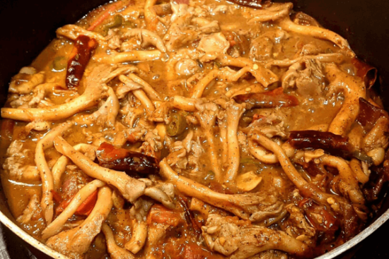 Oyster mushrooms in a dark curry with dried chilies on a pan