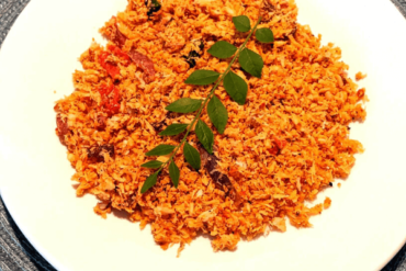 Shredded coconut relish or pol sambola with a curry leaf on top on a white plate