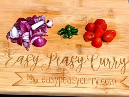 Onions, tomato and green chillies chopped on a cutting board