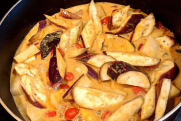 chopped aubergine, potatoes and tomatoes in a saucepan with spices and coocnut milk