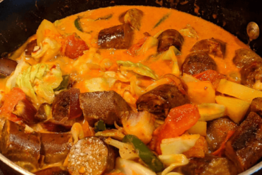 Red curry with chunks of potatoes, sausages, cabbage and tomatoes