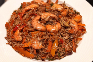 Fried rice topped with lots of fried shrimp on a white plate