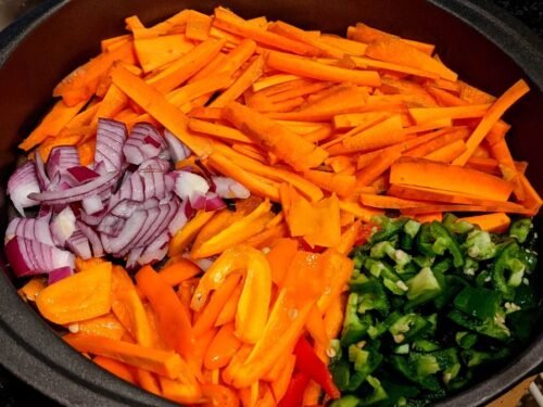 Chopped carrot, bell peppers, red onions and green chillies on a cutting board