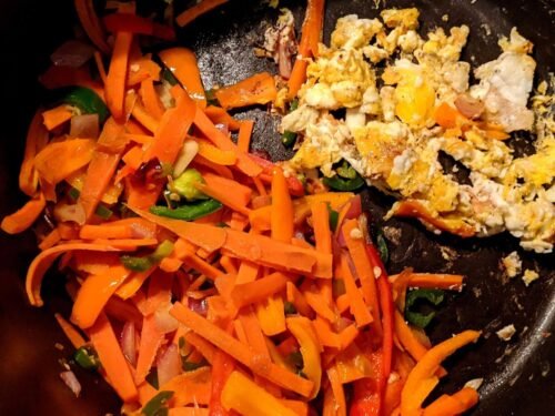 Fried vegetables and a scrambled egg on the pan