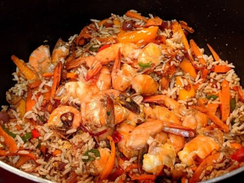 Fried rice topped with fried shrimp on a pan