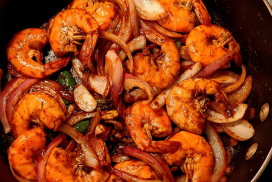 fried shrimp in a pan with chopped onions and garlic