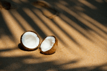 Two broken halves of a coconut against a beige background