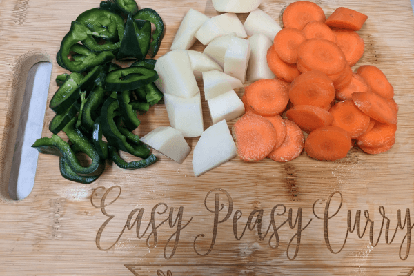 chopped peppers, potato and carrots on a cutting board