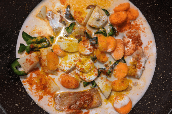 Coconut milk curry of catfish, vegetables and spices on a pan