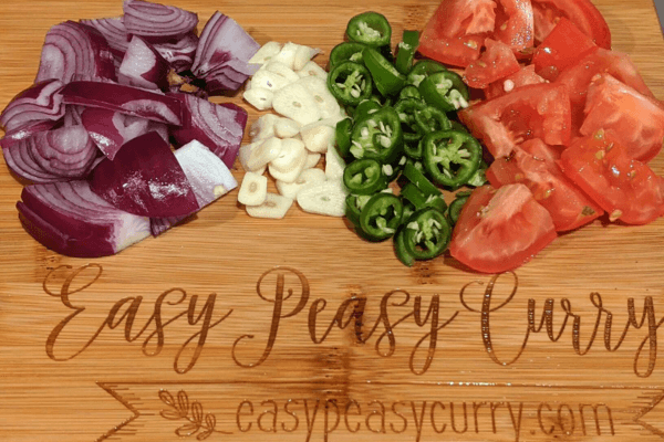 chopped onions, garlic, green chili and tomato on a cutting board