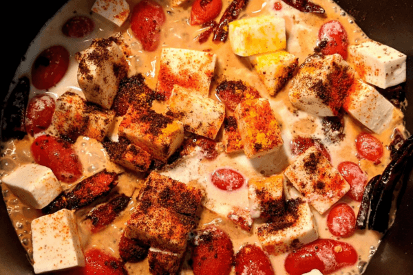 tomatoes and paneer cubes in a coconut milk curry with spices