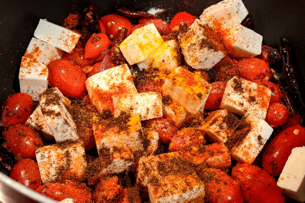 tomatoes and paneer cubes in a pan with spices