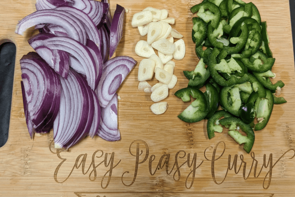 Chopped onions, jalapenos, and garlic on a cutting board