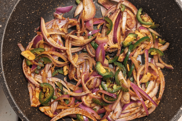 chopped onions, garlic and jalapenos stir fried on a pan
