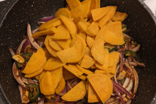 chopped onions, garlic and jalapenos and chopped sweet potatoes stir fried on a pan