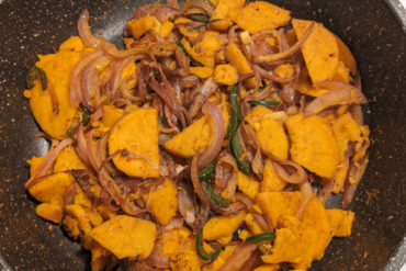 chopped onions, garlic and jalapenos and chopped sweet potatoes stir fried on a pan