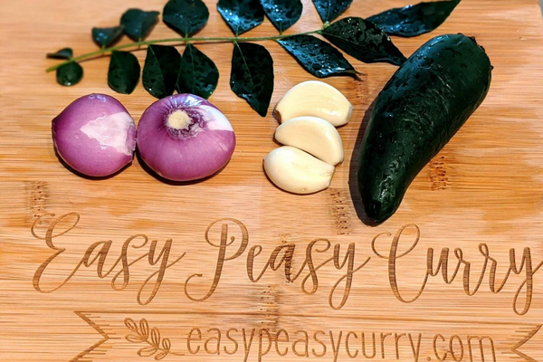 Onions, garlic, jalapenos and curry leaves on a cutting board